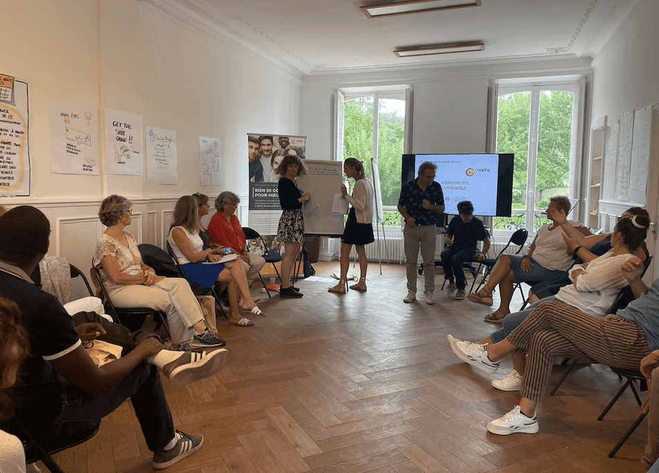 plusieurs hommes et femmes assis en rond dans une grande salle