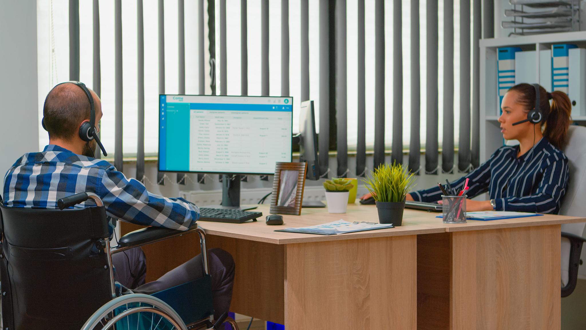 une femme et un homme en fauteuil roulant travaillant dans un openspace
